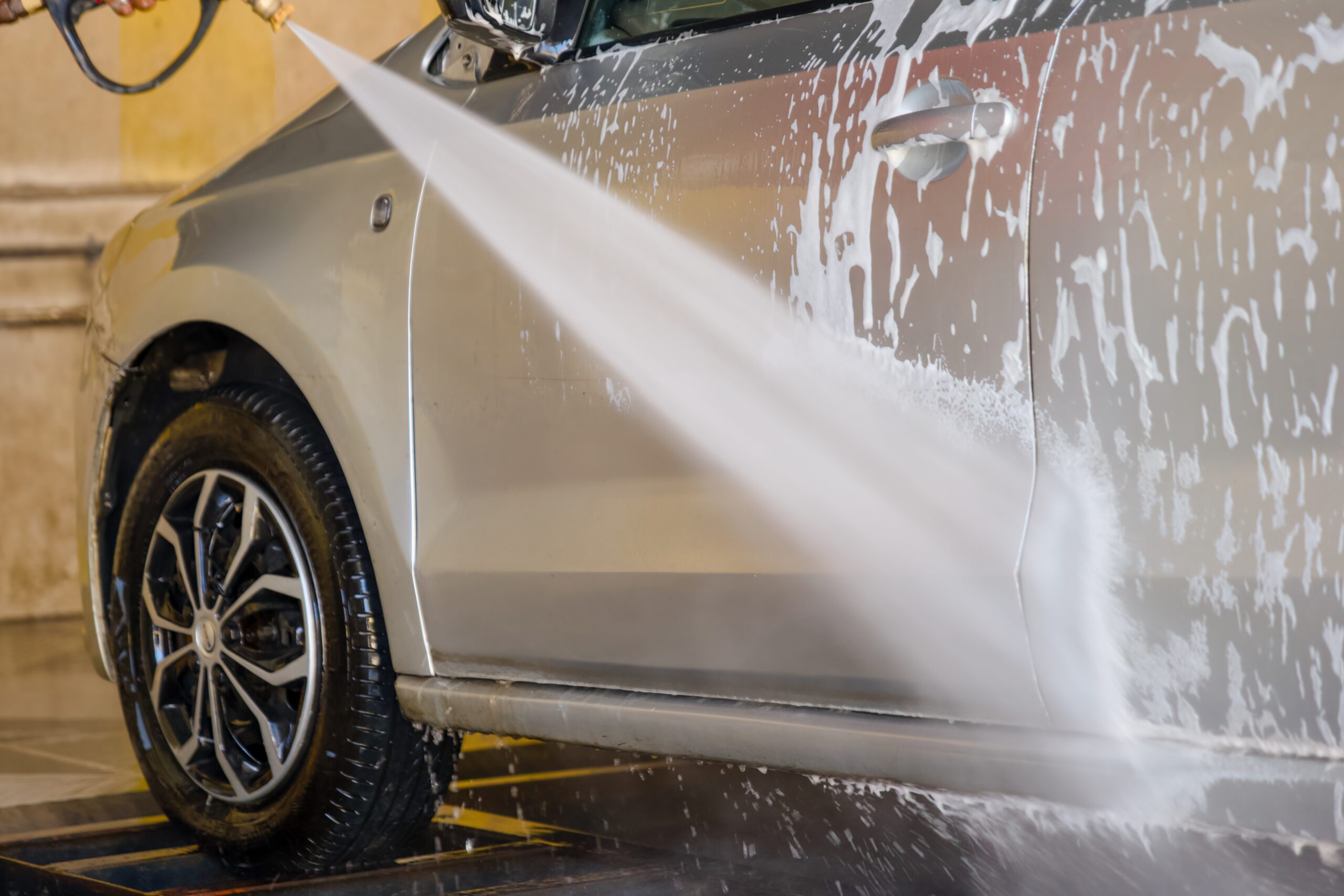 A silver car undergoing powerwashing to display why Ingress Protection is important on vehicles.